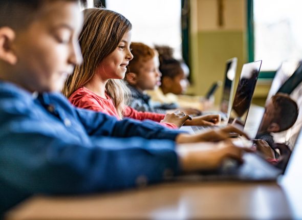 Digital native students e-learning over computers at school.